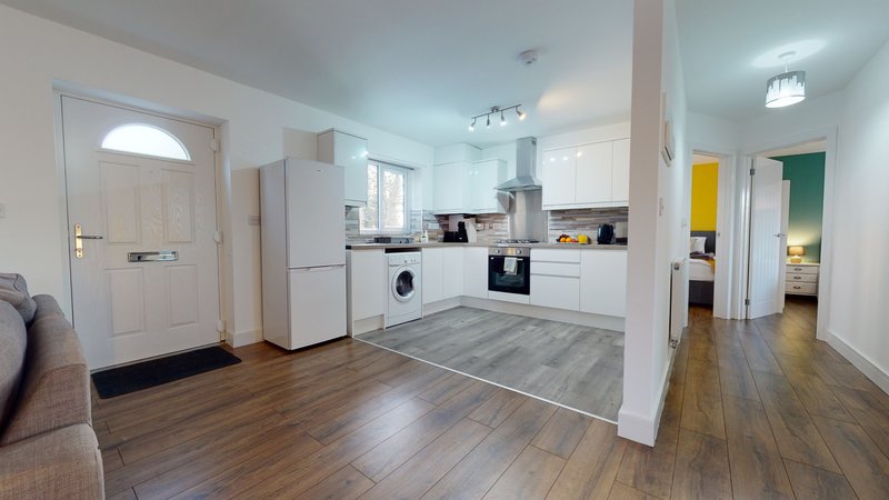 Open-plan kitchen and living area with white cabinetry, wooden flooring, and modern appliances