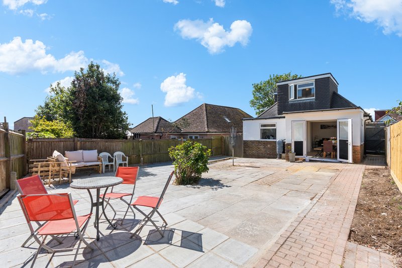 Spacious garden patio with outdoor seating, modern extension, and neighboring properties