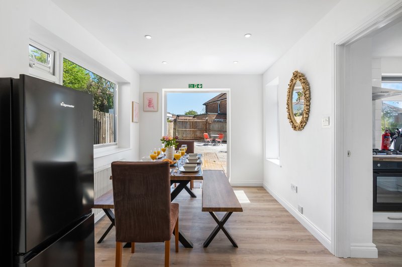 Open-plan kitchen and dining area with black refrigerator, wooden dining table, and access to garden
