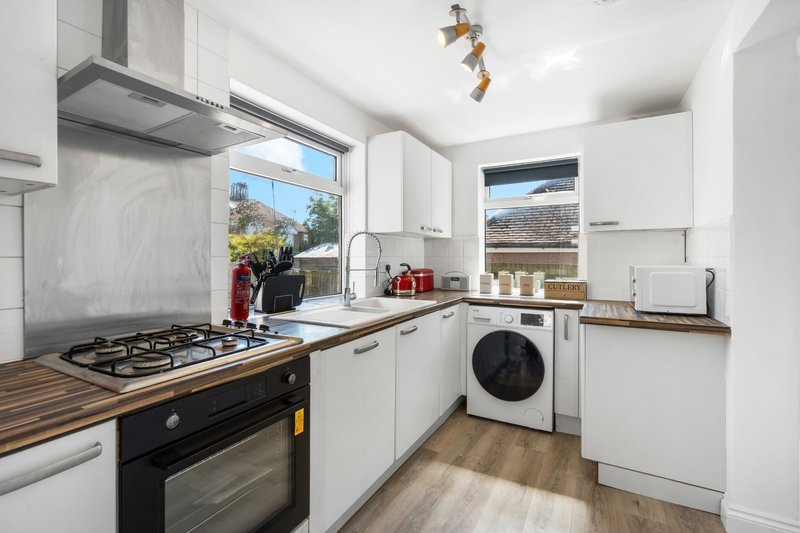 Modern kitchen with white cabinets, wooden worktops, black gas oven, and washing machine
