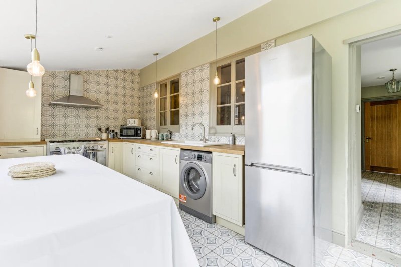 Modern kitchen with white cabinetry, stainless steel appliances, island counter and patterned backsplash