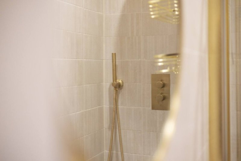 Modern shower enclosure with brass fixtures, cream subway tiles and glass panel