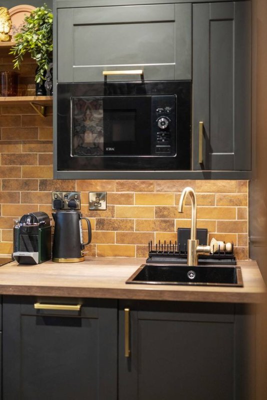 Modern kitchen with black cabinets, terracotta brick backsplash, built-in microwave and sink