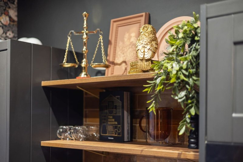 Wooden shelving unit displaying scales of justice, decorative figurines, plants and books