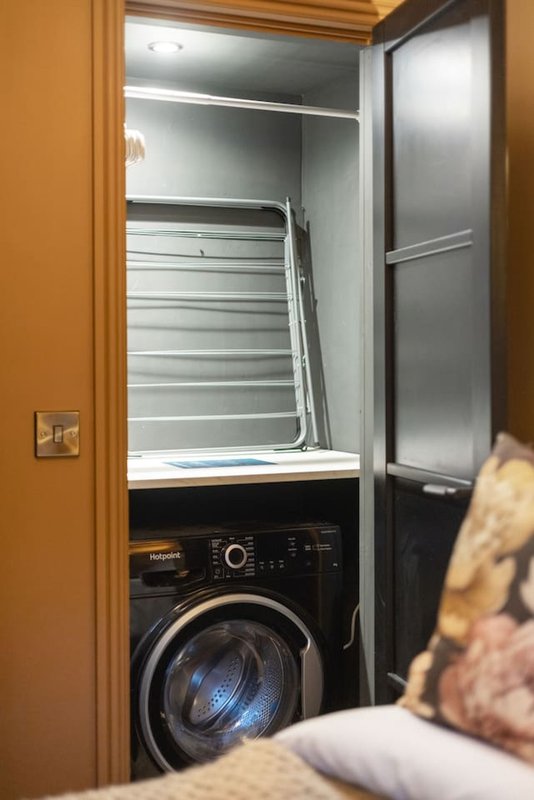Laundry closet with black front-load washing machine and white drying rack