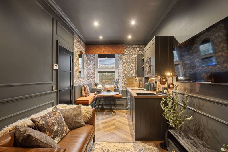 Modern kitchen with dining area, leather seating, wooden flooring and patterned wallpaper