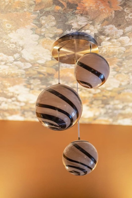 Modern pendant light fixture with three hanging spheres against textured ceiling