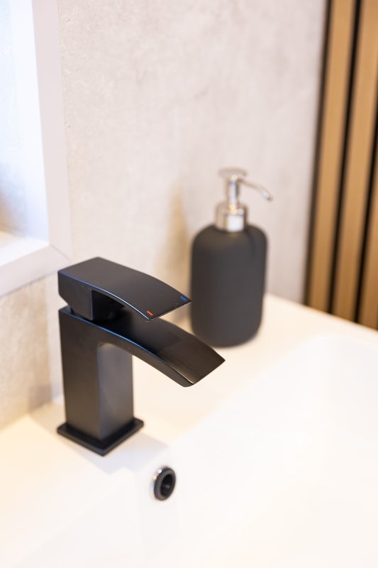 Modern bathroom sink with black faucet, soap dispenser, and neutral décor