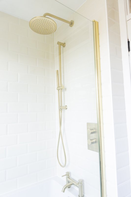 Modern bathroom shower with brass fixtures, rainfall showerhead and white subway tile walls