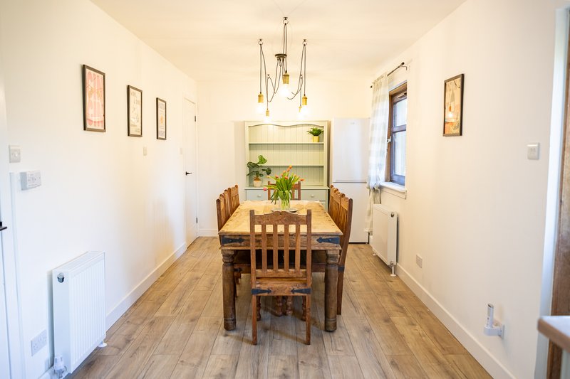 Dining room with wooden table, chairs, pendant lighting and built-in shelving