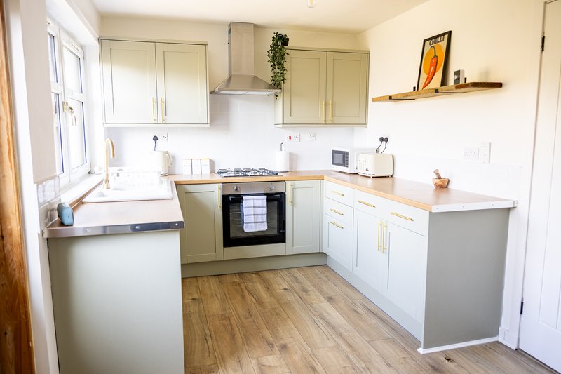 Modern kitchen with cream cabinets, built-in oven, wooden flooring and window