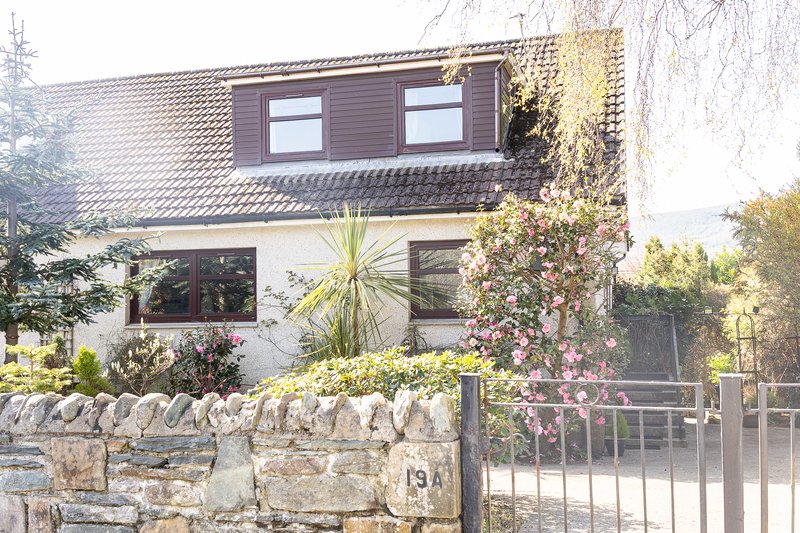 Modern two-story house with stone wall boundary and climbing ivy plants