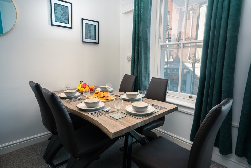 Dining room with wooden table, four black chairs, place settings and city view