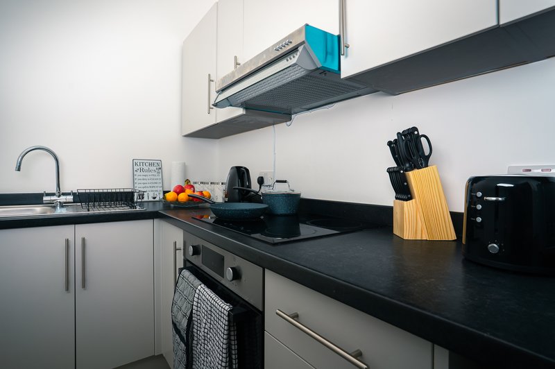 Modern kitchen with white cabinetry, black countertop, stainless steel appliances and knife block