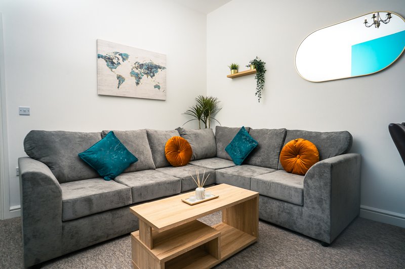 Modern living room with gray corner sofa, wooden coffee table, decorative cushions and wall art