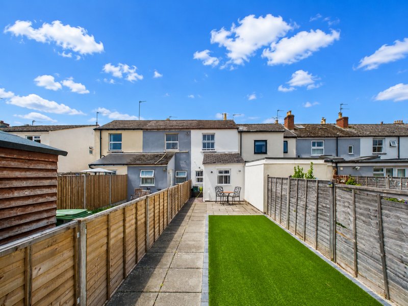Terraced house rear garden with wooden fencing, paved patio and artificial grass