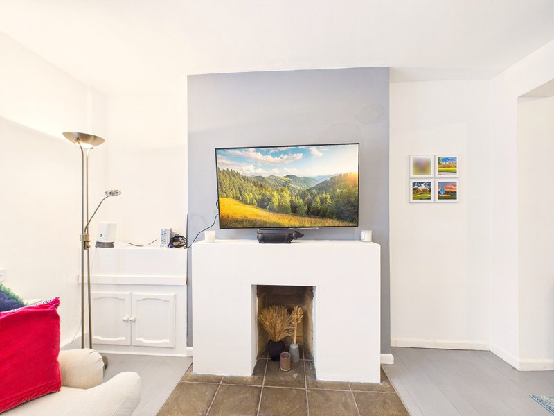 Modern living room with white fireplace, wall-mounted TV, red cushion, and floor lamp