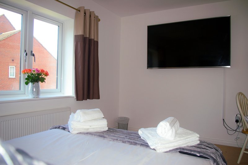 Bedroom with double bed, wall-mounted TV, window with curtains and exterior view