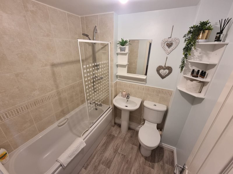 Modern bathroom with shower enclosure, pedestal sink, toilet, and wall-mounted shelving