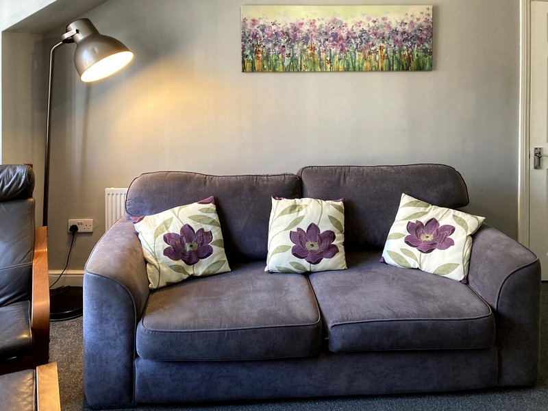 Grey upholstered sofa with purple flower cushions and floor lamp in living room