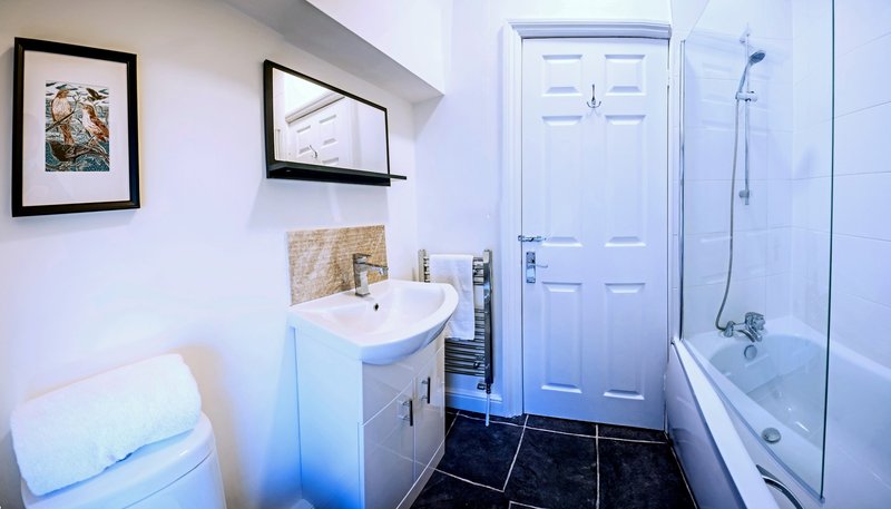 Clean bathroom with white sink vanity, toilet, shower enclosure and framed wall art