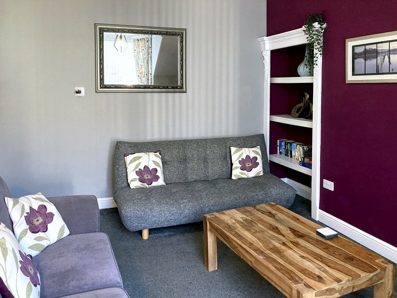 Living room with gray sofa, armchair, wooden coffee table and purple accent wall