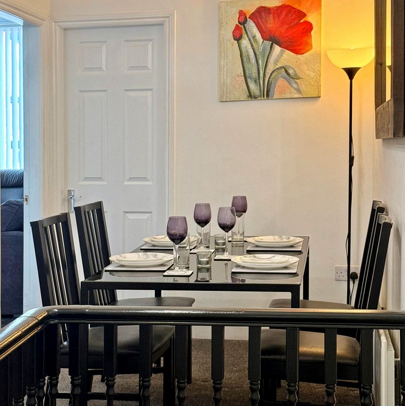 Dining room with black table, chairs, place settings, wine glasses and floral wall art