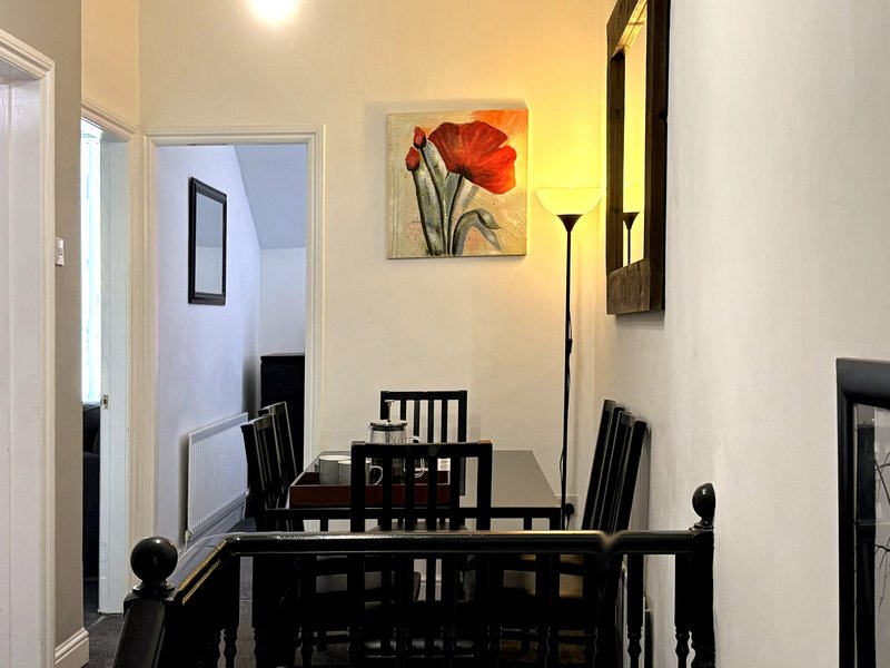 Dining area with black table, chairs, and red flower artwork on cream wall