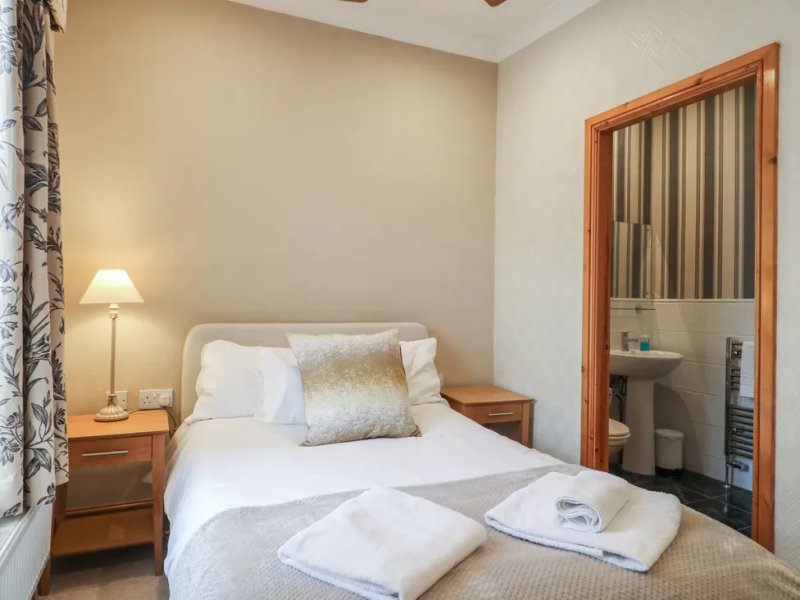 Bedroom with double bed, wooden nightstands, lamp, and striped curtains