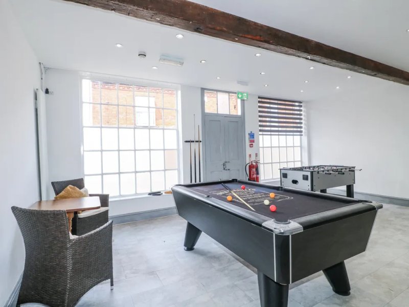 Games room with pool table, foosball table, wicker chair and large windows