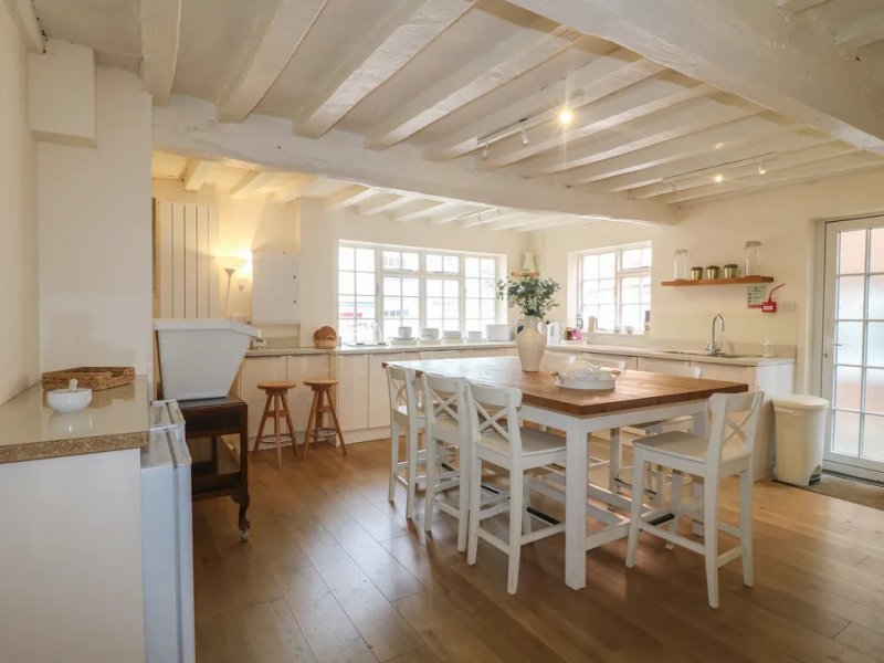 Open-plan kitchen and dining area with island, wooden beams, and large windows