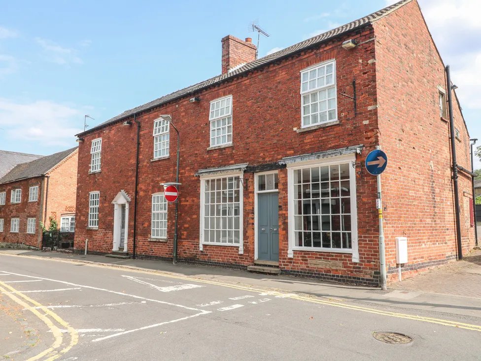 Red brick period property with multiple windows, street frontage and clear blue sky