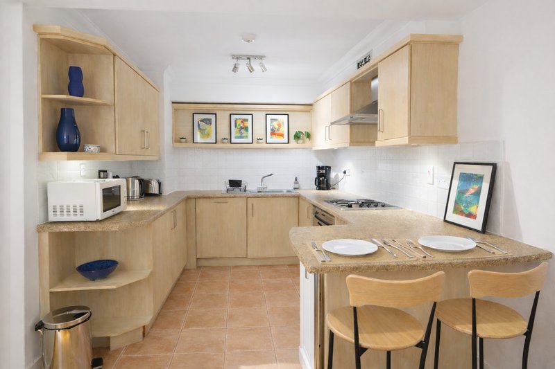 Modern kitchen with wooden cabinets, white countertops, island seating, and dining area