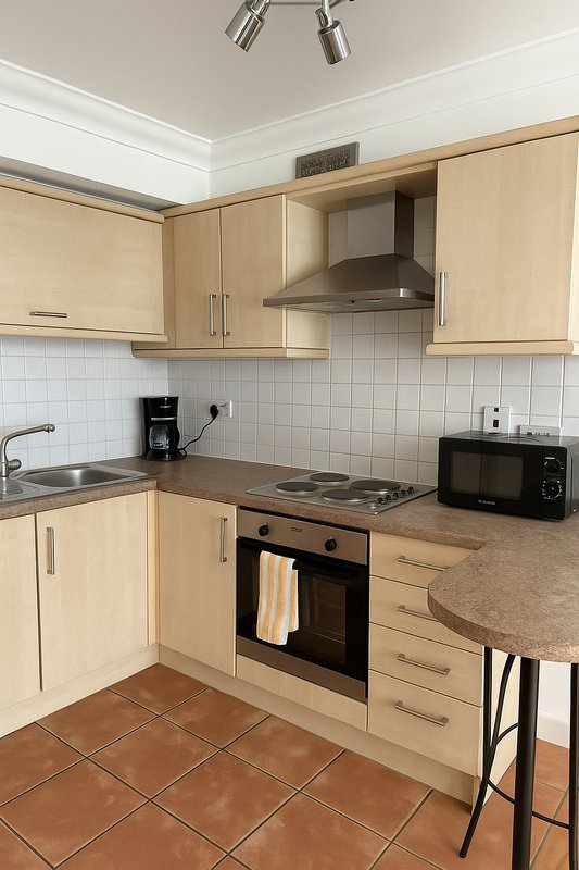 Modern kitchen with light wood cabinets, built-in oven, hob, extractor hood and tile flooring
