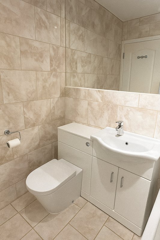 Bathroom with toilet, pedestal sink, cream tile walls and tiled floor