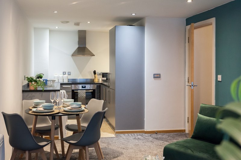Open-plan kitchen and dining area with round table, black chairs, and modern appliances
