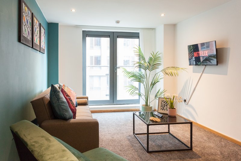 Modern living room with brown sofa, green accent wall, coffee table and potted plant