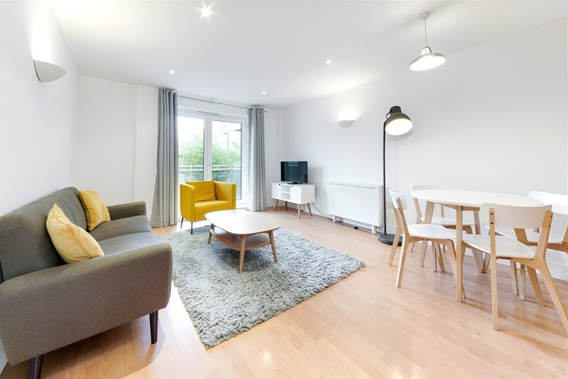 Open-plan living room with grey sofa, yellow armchair, wooden dining table and chairs