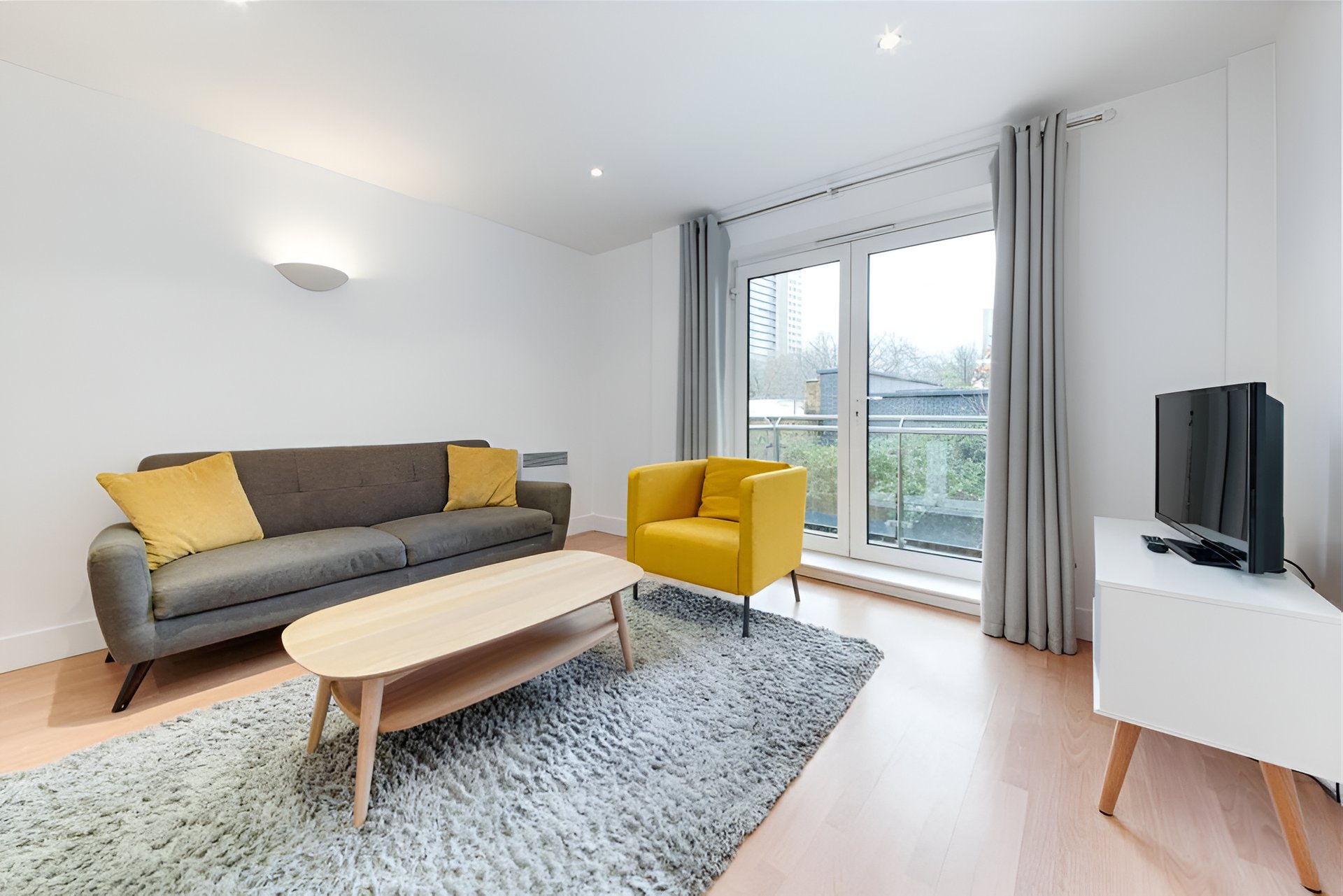 Modern living room with grey sofa, yellow armchair, wooden coffee table and city views