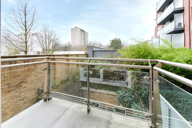 Modern balcony with glass and metal railings overlooking urban courtyard and buildings