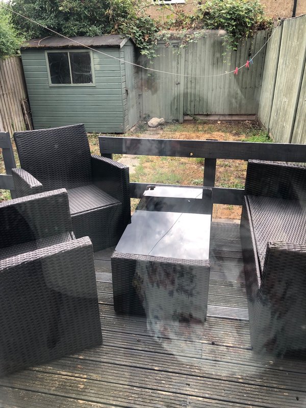 Outdoor garden seating area with black rattan furniture and decking
