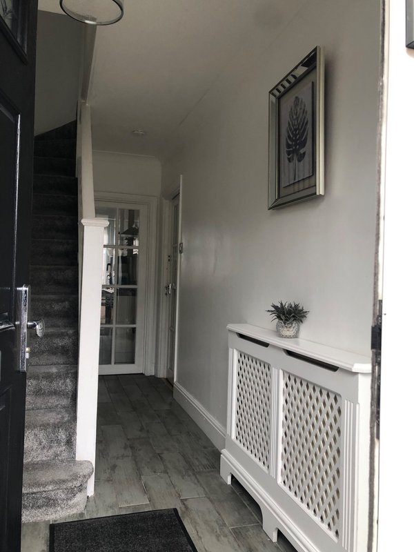 Modern hallway with white walls, dark wooden floor, white storage unit and framed artwork