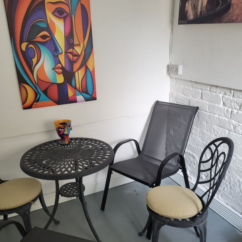 Modern seating area with round black table, chairs, colorful wall art and white brick wall