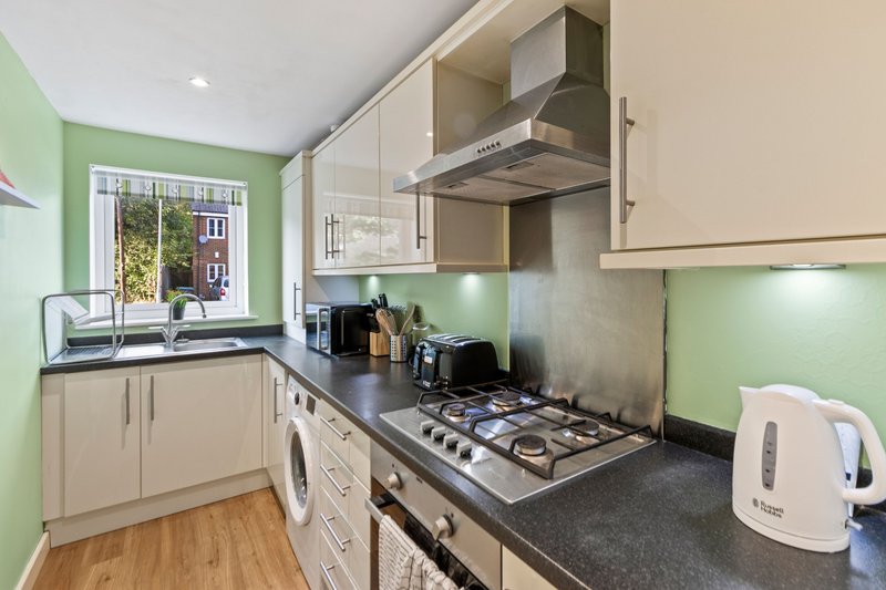 Modern kitchen with cream cabinets, gas hob, washing machine and green accent walls
