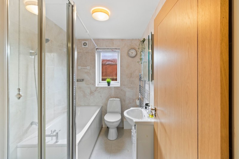 Clean modern bathroom with shower enclosure, toilet, sink and wooden door