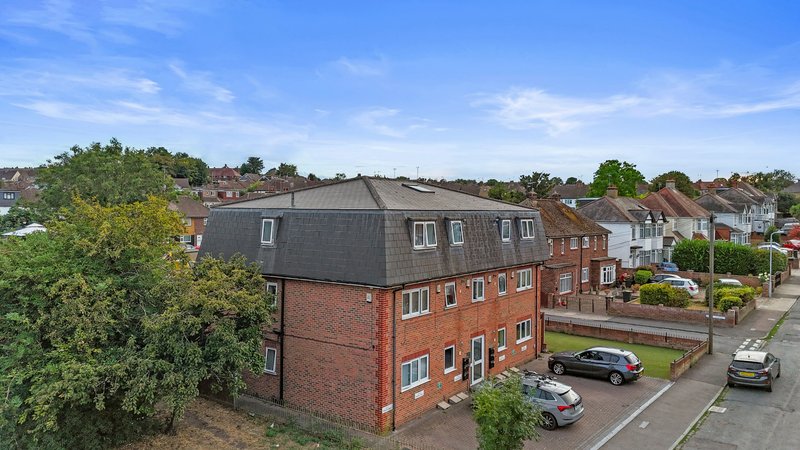 Red brick residential building with slate roof, street frontage, parked cars and suburban neighborhood