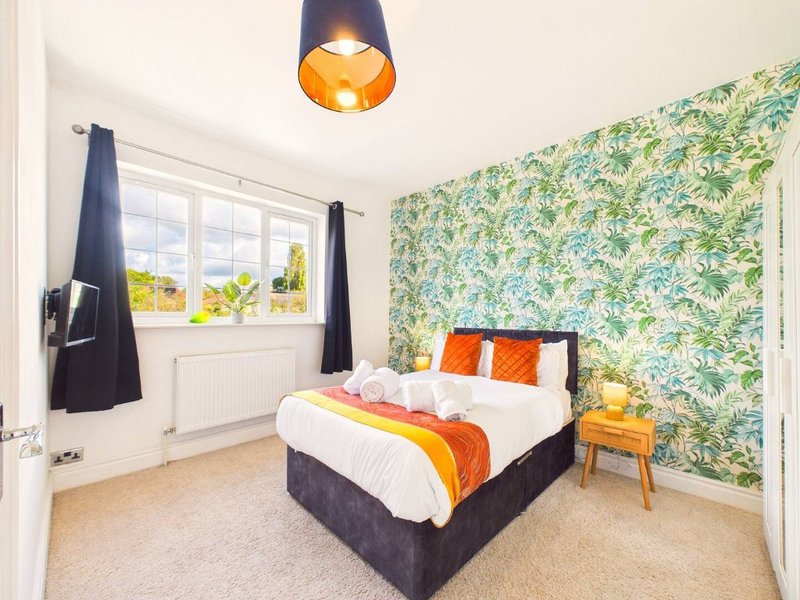 Bright bedroom with double bed, floral wallpaper, pendant lamp, and window with garden view