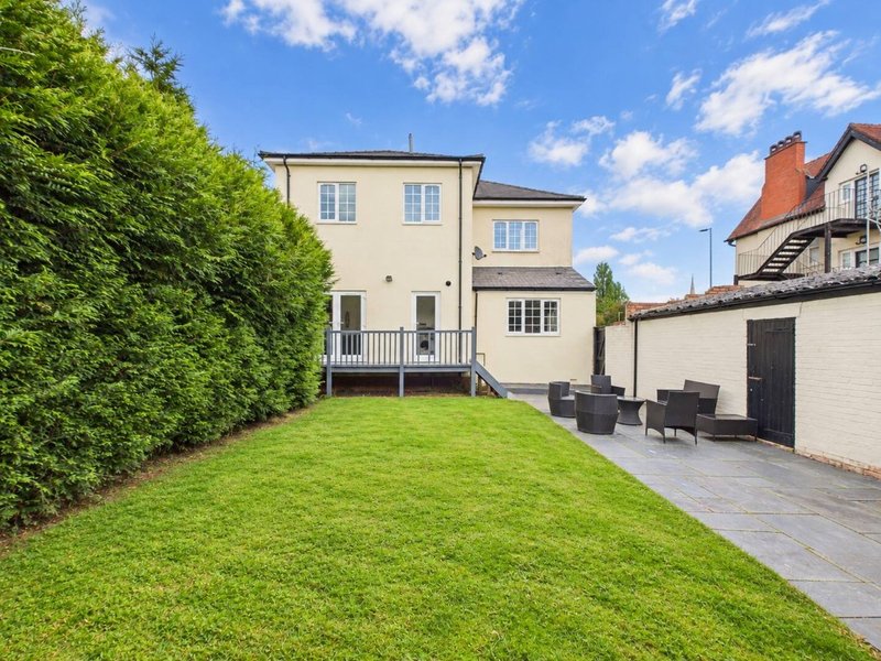 Cream-coloured house with garden, patio seating area and manicured lawn