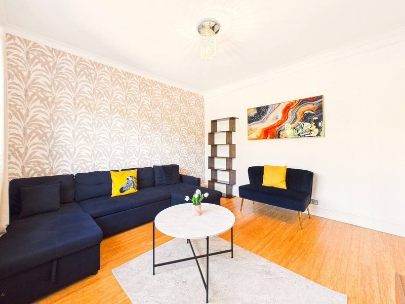 Modern living room with navy sectional sofa, accent armchair, white coffee table and wooden flooring