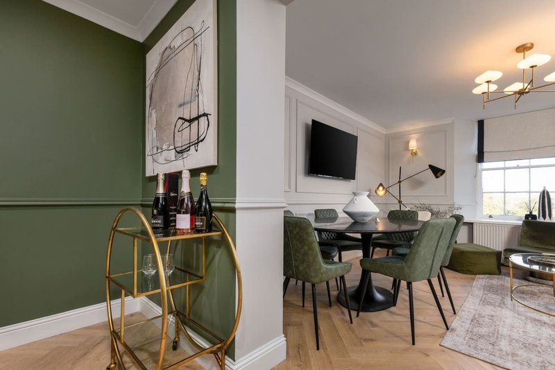 Open-plan living and dining area with green accent wall, dining table, and modern furnishings